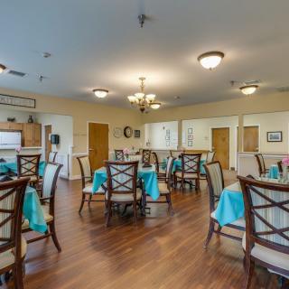 A spacious dining room with elegantly set tables and bright lighting.