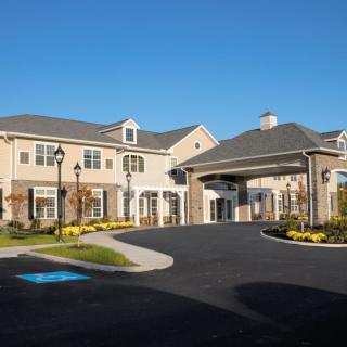 A modern residential building with a covered entrance under a clear blue sky.