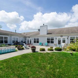 A spacious residential house with a large patio and well-maintained yard under a cloudy sky.