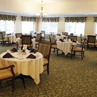 An elegant dining room with neatly arranged tables and chairs, featuring chandeliers and stylish decor.