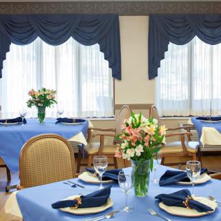 A well-decorated dining room with blue tablecloths and elegant floral centerpieces.