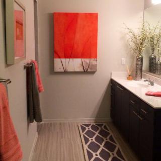 A modern bathroom with abstract orange artwork and complementary decor.