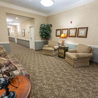 A cozy lobby seating area with armchairs, artwork, and a warm ambiance in a hallway.