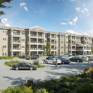 A multi-story apartment building with a surrounding parking lot filled with cars under a clear blue sky.