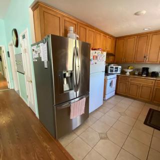 A modern kitchen featuring wooden cabinets, a stainless steel refrigerator, and a white stove.
