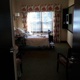 A hospital room with a bed and medical equipment near a window.