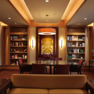 A cozy library with wooden bookshelves, comfortable seating, and warm lighting.