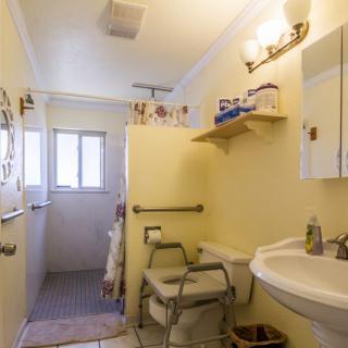 A small bathroom with accessible features, including handrails and a shower.