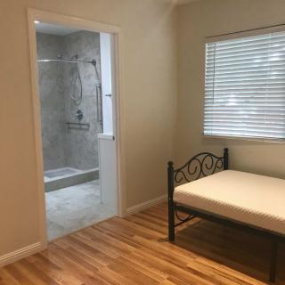 A cozy bedroom with a single bed and a view into an adjacent bathroom.