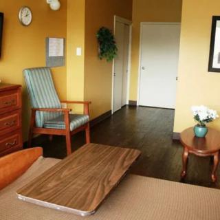 A cozy hotel room featuring a comfortable chair, wooden furniture, and decorative elements.