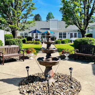 A tranquil patio area with a central fountain surrounded by benches and lush greenery.