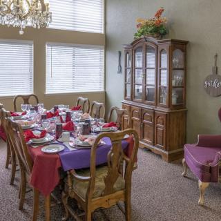 A dining room with a long table set for a meal, featuring a chandelier and china cabinet.