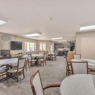 A spacious, well-lit dining area with multiple tables and chairs arranged for community gatherings.