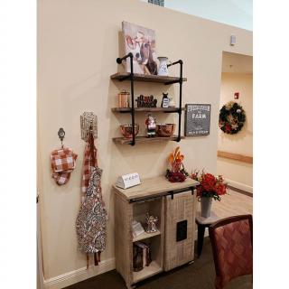 A cozy interior corner featuring decorative shelves, a cabinet, and festive wall hangings.