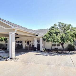 A building entrance with a covered driveway and surrounding trees.