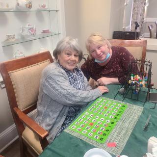 Two elderly women enjoying a game of bingo at a table indoors.
