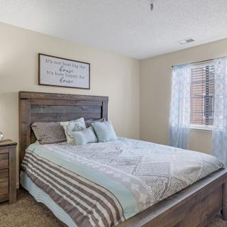 A cozy bedroom with a neatly made bed, featuring soft bedding and a bright window.