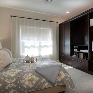 A cozy bedroom with a large bed and dark wood wardrobe.