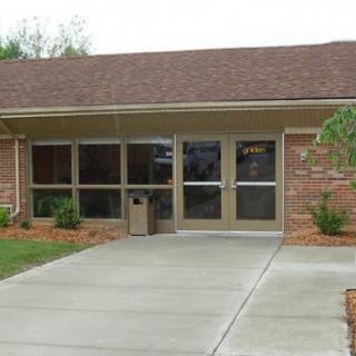 A small brick building with large windows and an entrance walkway.