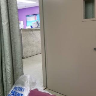 A view of a hospital doorway leading to a waiting area with purple walls.