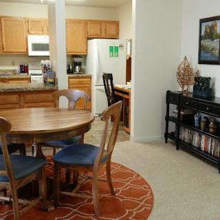 A cozy dining area with a wooden table, chairs, and a view into the kitchen.