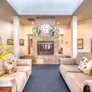 A cozy living room with a central fireplace, decorated with sofas and a large wall clock.