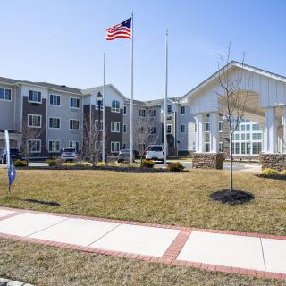 A residential apartment complex with an American flag flying in front on a sunny day.