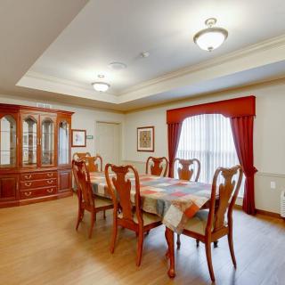 A well-appointed dining room with a wooden table and chairs, accented by drapes and a chandelier.