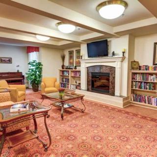 A cozy living room with a fireplace, bookshelves, and comfortable seating areas.