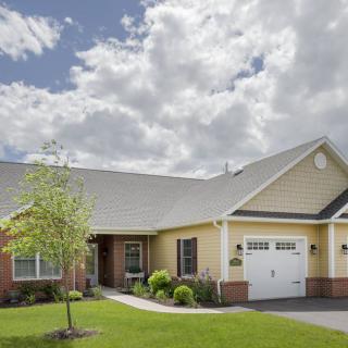 A single-story residential house with a well-maintained lawn and a two-car garage under a cloudy sky.