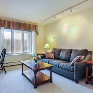 A cozy living room with a comfortable sofa, wooden coffee table, and lamp beside a large window.