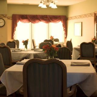 A cozy dining room with elegant table settings and soft sunlight streaming through the windows.