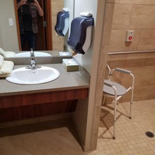 A spacious bathroom equipped with a sink, mirror, towels, and a stool for accessibility.
