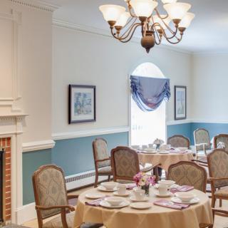 A well-decorated dining room with a chandelier, elegant tables, and chairs.