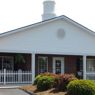 A building with a white facade and decorative landscaping in the foreground.