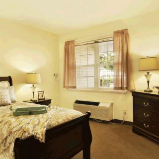 A cozy and well-furnished bedroom with a bed, dresser, and lamps.