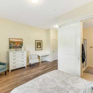 A cozy bedroom featuring a dresser, chair, and desk with decorative artwork on the walls.