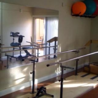 A rehabilitation gym featuring exercise equipment and ballet barres for therapy.