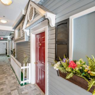 A creatively designed indoor hallway resembling the exterior of a house, complete with windows and a red door.