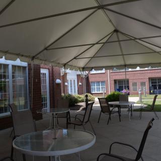 A covered patio with tables and chairs outside a building.