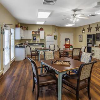 A cozy dining area with tables and chairs, featuring a kitchenette and decorative elements.