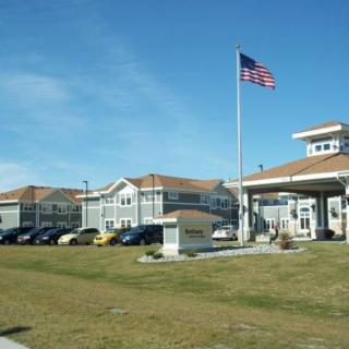A sunny day view of a building complex with an American flag on the lawn.
