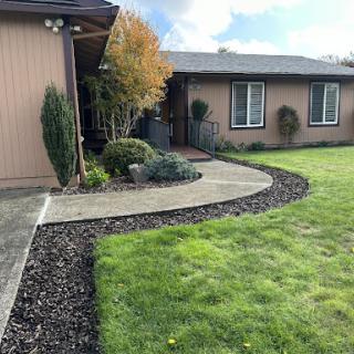 A beautifully landscaped front yard featuring a curved pathway and lush green lawn.