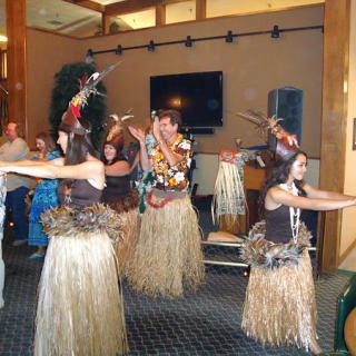 A group of performers dancing in traditional attire indoors.