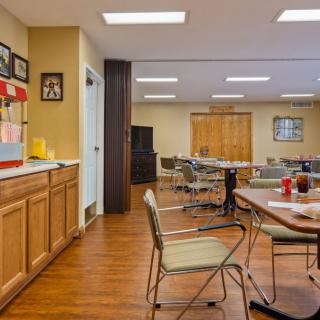 A community room with tables, chairs, a popcorn machine, and wood flooring.