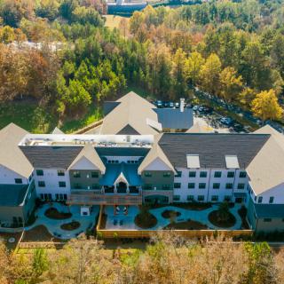 Aerial view of a large building surrounded by autumn trees and forest.