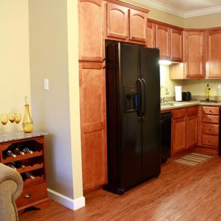 A cozy kitchen with wooden cabinets, a black refrigerator, and a wine rack.
