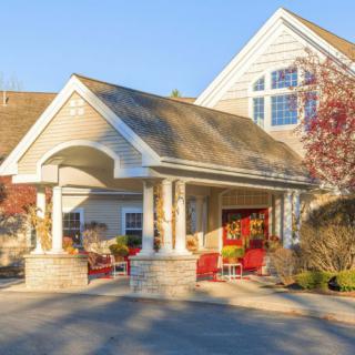A welcoming entrance to a residential building surrounded by trees and landscaping.