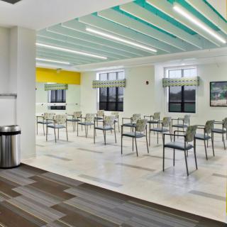 A modern, empty cafeteria with tables and chairs arranged neatly under bright lighting.
