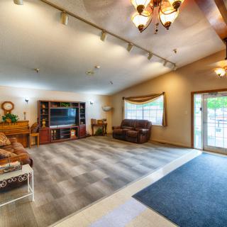 Spacious living room with cozy seating and a large television, featuring ample natural light.